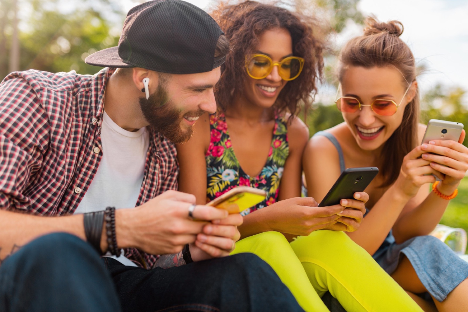 Amigos sorrindo usando o celular ao ar livre